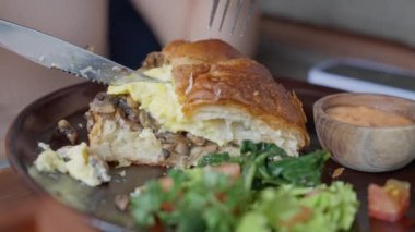 Sandviç kruvasan, peynirli ve sebzeli sandviç, kadın lezzetli bir kruvasan yiyor. Ağır çekim. Yüksek kalite 4k görüntü