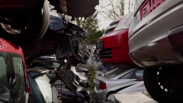 在垃圾场 一辆灰色汽车被堆放在另一辆红色汽车上 车轮和汽车照明四处散落 高质量的4K镜头 — 图库视频影像