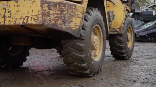 Żółty Buldożer Dużymi Kołami Polnej Drodze Obok Stosu Samochodów Opony — Wideo stockowe