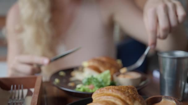 サンドイッチクロワッサン チーズと野菜とサンドイッチ 女性はバックグラウンドでおいしいクロワッサンを食べます スローモーション 高品質の4K映像 — ストック動画