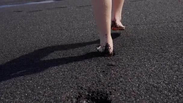 Dziewczyna Spaceruje Boso Czarnej Piaszczystej Plaży Woda Delikatnie Pieści Jej — Wideo stockowe