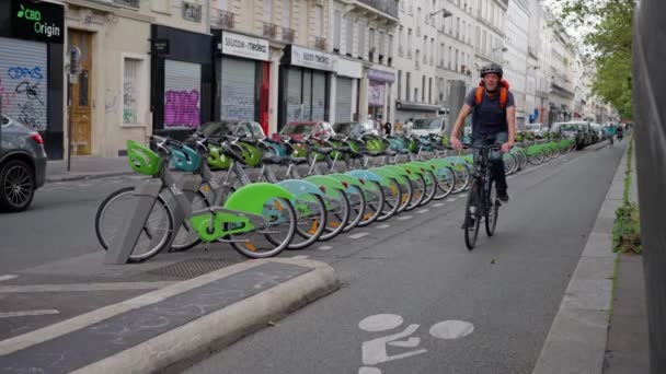 Homem Está Pedalando Uma Rua Asfalto Lado Uma Linha Bicicletas — Vídeo de Stock
