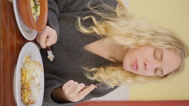 一位女士正在餐桌边享用着一餐 用叉子吃着美味的食物 她优雅的姿势展示了用新鲜的配料和蔬菜烹调的艺术 垂直录像 慢动作4K — 图库视频影像