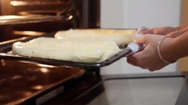 Bir kadın fırına çiğ khachapuri katılmış bir çarşaf koyar. Gürcistan yemekleri, Adjarian Khachapuri. Fırınla yemek pişirmek. Peynirli hamur pişirmek. Yüksek kalite 4k görüntü