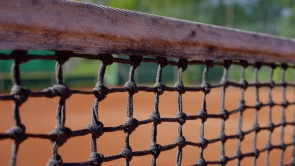 一张由网眼和铁丝网构成的网球网的详细照片 它横跨球场上的一个木制框架 在模糊的背景下 女人用球拍和慢动作击中了一个网球 高质量的 — 图库视频影像