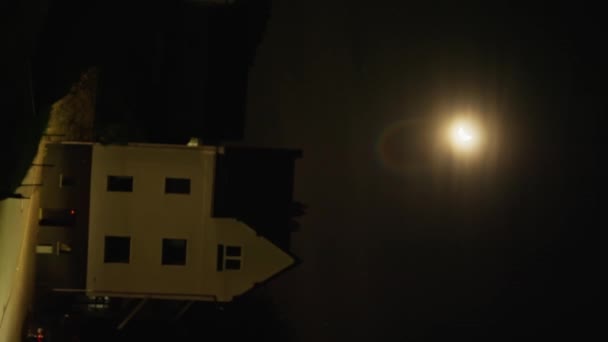 午夜时分 一座房子被黑暗包围 灯火通明 满月挂在天空中 在建筑物的正面和窗户上投射出柔和的光芒 4K视频 — 图库视频影像