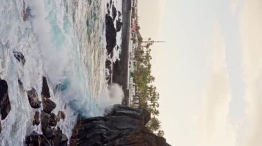 Dev okyanus dalgalarının Tenerife Sahili 'nde büyük kaya taşlarıyla çarpışması ve köpürmesi. Derin mavi okyanus suyuyla buluşuyor. Dikey video. Ağır çekim. Yüksek kalite 4k görüntü