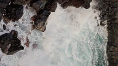Dev okyanus dalgalarının Tenerife Sahili 'nde büyük kaya taşlarıyla çarpışması ve köpürmesi. Derin mavi okyanus suyuyla buluşuyor. Dikey video. Ağır çekim. Yüksek kalite 4k görüntü