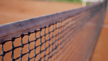 Bir kil tenis kortu ve sporun yoğunluğunu ve odak noktasını yansıtan bir oyuncu şuta karşılık vermeye hazır. Yavaş çekim