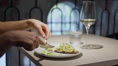 Avokado tostu ve şarabın tadını çıkaran birinin yakın çekimi. Modern yemek deneyimi yakalandı. Yavaş çekim 4k