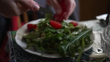 Mutfak ortamında domatesli taze yeşil salata hazırlayan ellerin yakın çekimi. Sağlıklı yeme kavramı.