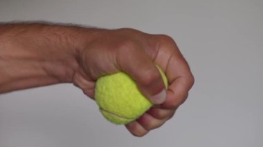 Sarı bir tenis topunu sıkan bir el stresi yönetmek ya da egzersiz yoluyla el kaslarını güçlendirmek için idealdir.
