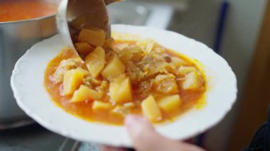 Lüks ve rahatlatıcı bir patates ve lahana çorbası, sıcaklığı ve rahatlığı yansıtan beyaz bir tabağa servis ediliyor. Ukrayna yemeği. Ukrayna çorbası. Yavaş çekim