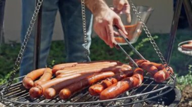 Kapalı çekimde, açık havada lezzetli sosisler pişirirken çekilmiş bir resim. Yaz barbekü etkinliği için ideal. Yavaş çekim