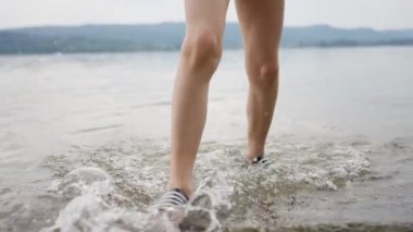 Bir çocuk sığ sularda ferahlatıcı bir yürüyüş, yaz atmosferini kucaklamak ve rahatlamak ister. Yavaş çekim