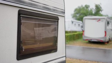 Huzurlu bir ortamda, birkaç kamp aracı canlı, yemyeşil bir kamp yerinde güzel bir şekilde düzenlenir.