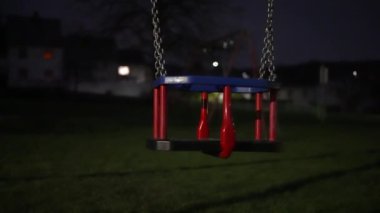 Otlar ve bitkilerle çevrili bir salıncak gece yarısı bir şehir parkında boş duruyor. Şehir ışıklarının elektrik mavisi karanlığa zıt düşer ve dingin bir dinlenme noktası yaratır. 4k