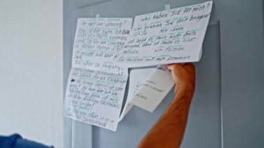 Bir kişi, üretkenliği önemli ölçüde artırmak ve Almancayı daha iyi öğrenmek için, düzenli teknikler sergileyerek, duvarlara çeşitli notlar asar.