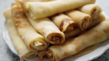 Mutfakta bir tabakta ev yapımı krep. Sıcak bir mutfak ortamında, beyaz bir tabakta servis edilen taze yapılmış altın sarısı krepler var. 4k görüntü