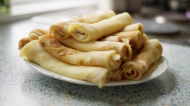 Mutfakta bir tabakta ev yapımı krep. Sıcak bir mutfak ortamında, beyaz bir tabakta servis edilen taze yapılmış altın sarısı krepler var. 4k görüntü