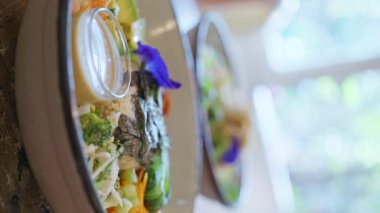 Avokado havuçlu sağlıklı salata sebzeler ve ahşap bir masada mavi çiçeklerle süslenmiş pirinç. Dikey görünüm. 4k görüntü