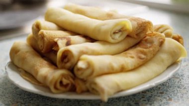 Beyaz bir tabakta sunulmuş ev yapımı krep yığını. Klasik bir kahvaltı ya da tatlı için mükemmel.