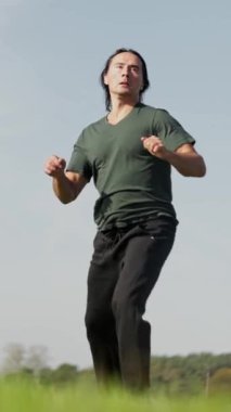 Huzurlu ve yemyeşil bir arazide barışa ilham veren bir adam dövüş sanatları icra ediyor. Adam tekmeler, ağır çekim.