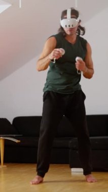 Bir insan modern, şık bir oturma odasında VR kulaklık ve kontrolörlerle oyun oynamakla derinden ilgilidir. Yavaş çekim