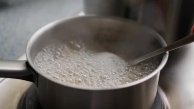 Kaynayan pirincin üzerine serpiştirilmiş renkli baharatlarla dolu bir kaşık, herkes için aromatik yemeğin özünü yakalıyor. Yavaş çekim 4k