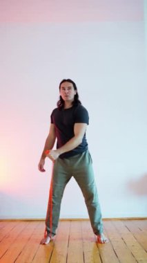 Bir adam, çağdaş, minimalist tasarlanmış bir ortamda direniş bandı egzersizleri yapıyor.