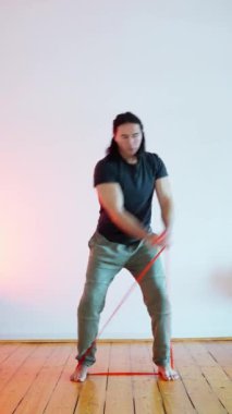 Bir birey, geniş bir çevrede elastik bant kullanırken güç eğitimi tekniklerini gösteriyor.