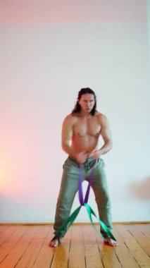 Evde eğitim kavramı, spor giyimli, sempatik bir adamın akşamları evde yerde lastik direnç kayışıyla egzersiz yapmasıdır. Yüksek kalite 4k görüntü