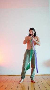 Aktif yaşam tarzı seçimleri. Odaklanmış bir adam, dayanıklılığını arttırmak için aktif olarak direnç bandı egzersizleri yapıyor ve lastik bantlarla yapılan genel sağlık alternatif egzersizleri, yüksek kaliteli 4K