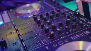 Canlı LED ışıkları ve sesleri karıştırmak için tasarlanmış sayısız düğmeleri gösteren bir DJ denetleyicisinin yakın plan görüntüsü