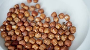 Mükemmel kavrulmuş fındık koleksiyonu temiz, el değmemiş beyaz bir tabakta sanatsal bir şekilde sergileniyor. Yavaş çekim 4k 