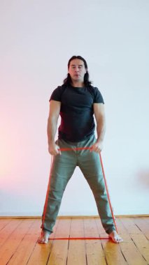 Bir adam çarpıcı bir sanatsal ortamda turuncu bir çerçeve kullanarak olağanüstü bir güç ve esneklik sergiler.