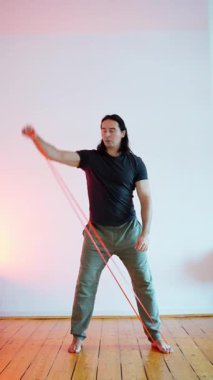 Bir adam, çağdaş, minimalist tasarlanmış bir ortamda direniş bandı egzersizleri yapıyor.