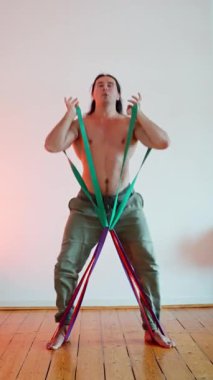 Tonlu bir atlet, etkili fitness ve dayanıklılık eğitimi alma amaçlı çeşitli direniş bandı egzersizleri sergiliyor