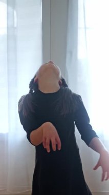 Çarşamba konsepti. Çarşamba Dansı. Dikey video. Çarşamba Addams kostüm giyen genç kız siyah bir elbise içinde dans ediyor. Ağır çekim. Dikey video. Yüksek kalite 4k görüntü