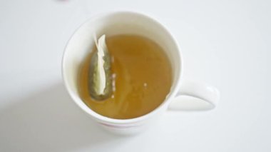 Çay demleme sanatını izleyin ve bir çay poşeti ılık bir bardak suda nazikçe demlenirken görün.