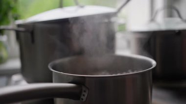 Sıcak bir tencereden yükselen buhar modern bir mutfakta yemek pişirmenin özünü yakalıyor..