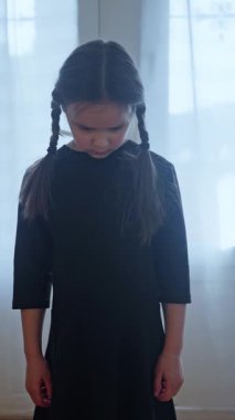 Siyah elbiseli kız ürkütücü bir şekilde kameraya bakıyor, Cadılar Bayramı için giyinmiş. Childs perili evde hayalet cadılar bayramı kostümü. Esrarengiz çocuk, siyah elbiseli kız korkutuyor. Korku, Thriller. 4k