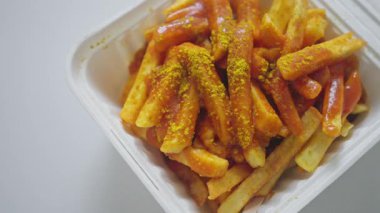 Lezzetli ve ağız sulandıran körili ketçap kaplı patates kızartması. Pakette güzelce yerleştirilmiş.