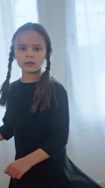Neşeli Çocuk Enerji ve Heyecan Dolu Parlak Aydınlık Bir Odada Heyecanla Dans Ediyor. Neşeli örgülü neşeli çocuk güneşli bir odada neşeyle dans eder, saf masumiyet ve mutluluğu yakalar.