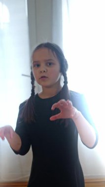 Neşeli örgülü neşeli bir çocuk güneşli bir odada neşeyle dans eder, saf masumiyet ve mutluluğu yakalar. Ağır çekim. Yüksek kalite 4k görüntü