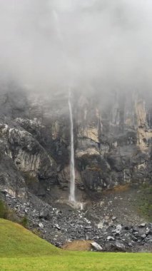 Sis, sis ve yemyeşil ile çevrili sarp kayalıklardan zarif bir şelale süzülüyor. İsviçre Dağları