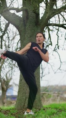 Tecrübeli bir dövüş sanatları ustası açık havada ileri tekme ve etkileyici duruşlar sergiliyor.