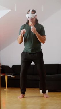 Sanal gerçeklik oyunlarına dalmış, modern teknolojiyi rahat bir ev ortamında sergiliyor.