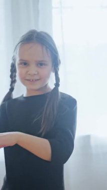 Zarif bir şekilde poz veren genç bir dansçı zarif duruşunu ve etkileyici hareketlerini yumuşak, sıcak ışıkta sergiliyor.