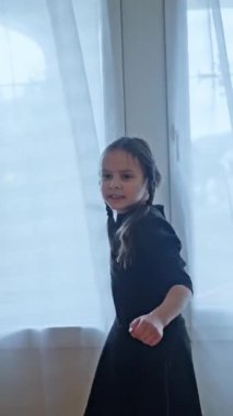 Neşeli örgülü neşeli çocuk güneşli bir odada neşeyle dans ediyor, saf masumiyeti yakalıyor. Neşeli Çocuk Enerji ve Heyecan Dolu Parlak Aydınlık Bir Odada Heyecanla Dans Ediyor. 4k görüntü